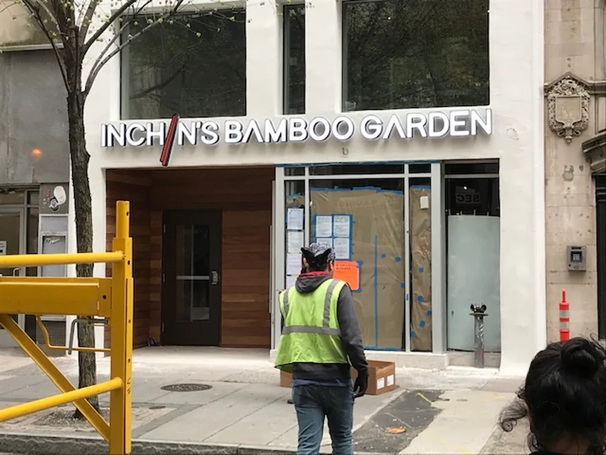 A VH installer in a hi-visibility vest at a storefront where the channel letters have just gone up