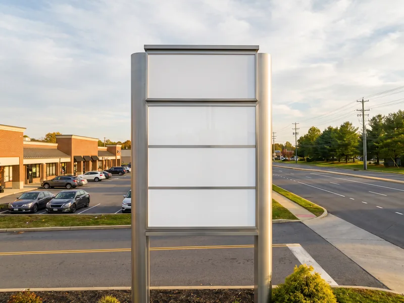 A multi-tenant pylon sign at the entrance of a suburban strip shopping center
