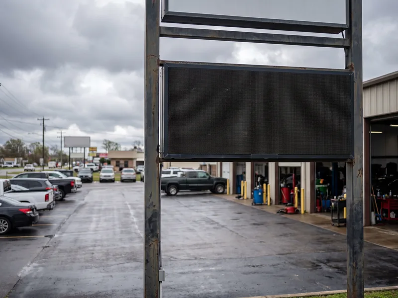 A roadside sign structure with an LED message panel outside an auto service business